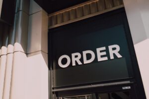 A sunlit view of a modern storefront with prominent 'Order' signage, highlighting a streamlined design.