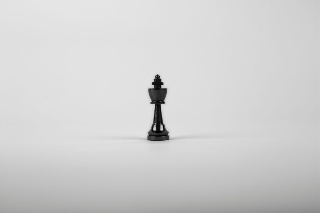 A minimalist black chess king piece on a white background, representing strategy and power.