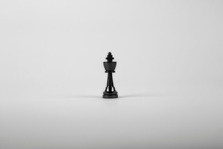 A minimalist black chess king piece on a white background, representing strategy and power.